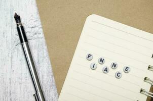 Word FINANCE with pen and notebooks on white wooden background photo