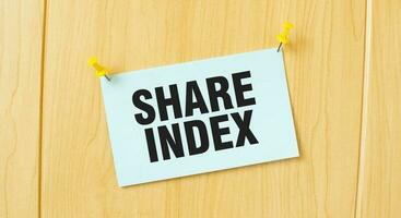 SHARE INDEX sign written on sticky note pinned on wooden wall photo