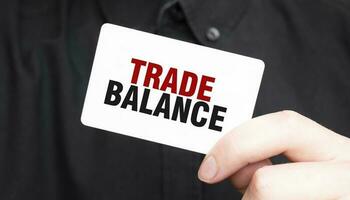 Businessman holding a card with text TRADE BALANCE, business concept photo