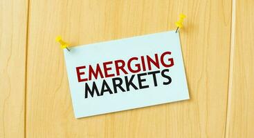 EMERGING MARKETS sign written on sticky note pinned on wooden wall photo