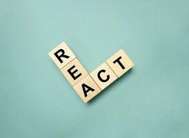 Word REACT on wooden blocks and green background photo