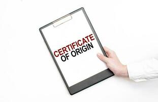 A businessman holds a folder with paper sheet with the text CERTIFICATE OF ORIGIN. Business concept. photo