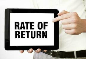 Text RATE OF RETURN on tablet display in businessman hands on the white background. Business concept photo
