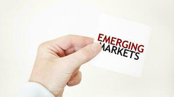 Businessman holding a card with text EMERGING MARKETS business concept photo