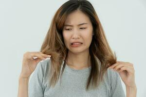 Asian woman very sad and upset looking at damaged hair, hair loss, hair thinning problem, vitamin deficiency, baldness, postpartum, biotin, zinc, menstrual or endocrine disorders, hormonal imbalance photo