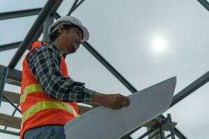 inspector or engineer is inspecting construction and quality assurance new house using a blue print. Engineer or architects or contactor work to build the house before handing it over to the homeowner photo