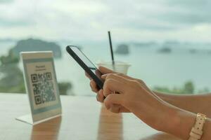 Woman use smartphone to scan QR code for order menu in cafe restaurant with a digital delivery. Choose menu and order accumulate discount. E wallet, technology, pay online, credit card, bank app. photo