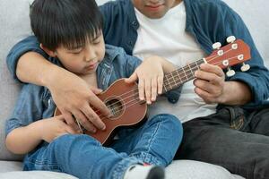 Happy single father playing learning music with the little boy. Funny family is happy and excited in the house. Father and son having fun spending time together. Vacant time, holiday photo