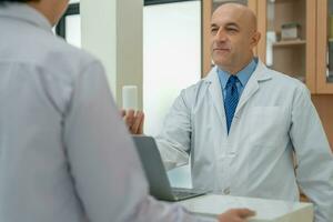 Professional pharmacist explain the results of a medicine to  patient and advice on medication. male doctor talks and records the patient's symptoms. Hospital , medical, health care photo