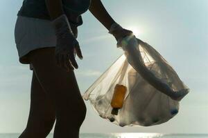 salvar océano. voluntario recoger arriba basura basura a el playa y el plastico botellas son difícil descomponer evitar daño acuático vida. tierra, ambiente, verdeado planeta, reducir global calentamiento, salvar mundo foto