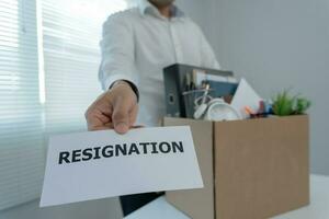 Stressful businessmen will resign from the company. He is lifting a brown paper box that holds personal items. resignation, job placement and vacancies concept. photo