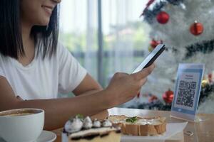 Woman use smartphone to scan QR code for order menu in cafe restaurant with a digital delivery. Choose menu and order accumulate discount. E wallet, technology, pay online, credit card, bank app. photo