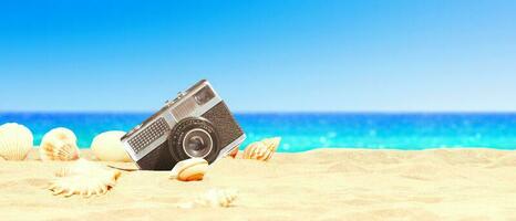 Landscape with seashells and old camera on tropical beach. photo