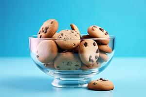 A glass bowl filled with chocolate chip cookies on a solid color background. photo
