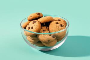 A glass bowl filled with chocolate chip cookies on a solid color background. photo