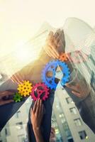 Handshaking between businessmen. Teamwork with colored gears. Double exposure with modern office photo