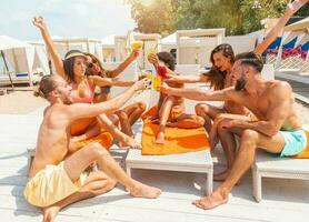 grupo de amigos con traje de baño bebida un cóctel en un playa sitio foto