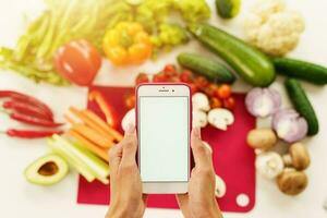 Cook follows a recipe of vegetables from the smartphone photo