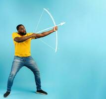 Black man ready to shoot the arrow from the bow. cyan background photo