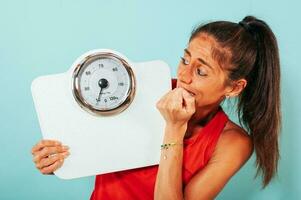 Woman is afraid of weight measurement with scale photo