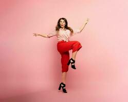 Brunette girl with red clothes jumps over a pink background. Concept of fashion and shopping with joyful expression photo