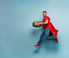 Deliveryman with pizzas acts like a powerful superhero. Concept of success and guarantee on shipment. Studio cyan background photo