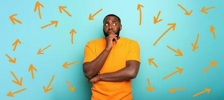 Confuse and pensive expression of a boy with many arrows to follow. cyan colored background photo