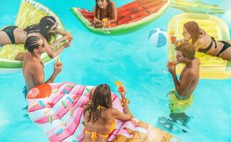 grupo de amigos en traje de baño bebida un cóctel en un nadando piscina foto