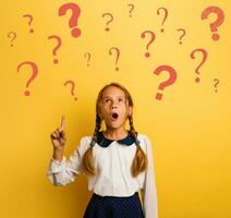 Young student is with shocked expression and indicates a lot of question marks. Yellow background photo