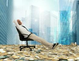 Successful businessman relaxing on a deckchair above an expanse of money photo