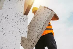 Mason applies glue to a thermal cladding on a construction site photo