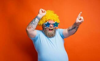 Fat amazed man with beard, tattoos and sunglasses dances music photo