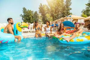 Group of friends in swimsuit enjoy in a swimming pool photo