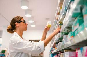 mujer trabajando en el farmacia mira para el medicina foto