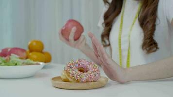 dieta y dieta. belleza cuerpo femenino delgado confundir donut. mujer con ropa de ejercicio logra el objetivo de pérdida de peso para una vida saludable, loca por la delgadez, cintura delgada, nutricionista. video