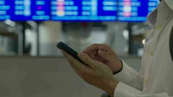 attività commerciale uomo utilizzando mobile Telefono per libro aereo biglietto attraverso in linea applicazione, seduta su viaggio controllo viaggio tempo su tavola a aeroporto, viaggiare, pagamento, dovuto, prenotazione, in linea, dai un'occhiata nel video