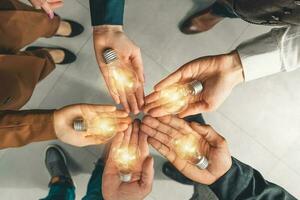 Teamwork and brainstorming concept with businessmen that share an idea with a lamp photo