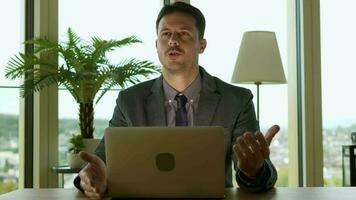 uma homem dentro uma terno é sentado às uma escrivaninha com uma computador portátil trabalhando dentro moderno escritório video