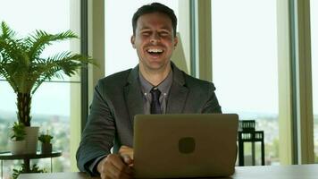 a man in a suit is smiling while using a laptop working in city office video