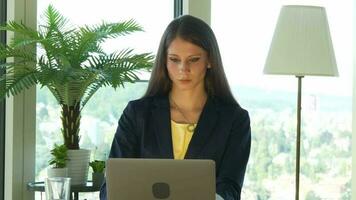 a woman in glasses is looking at her laptop working inside modern office video