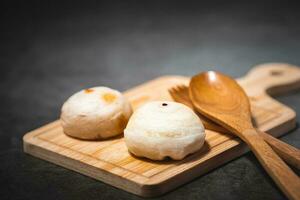 Traditional Chinese pastry with wooden spoon on plate against dark background photo