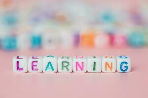 The word LEARNING from letter beads on pink background photo