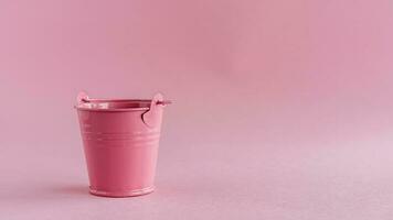 Mini colored tin pail or bucket on pink background photo