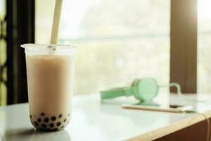 Bubble tea in plastic cup on white table with blurred background photo