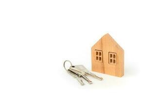 Wooden house model with keys on white background photo