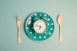 An alarm clock on an empty plate and cutlery set photo