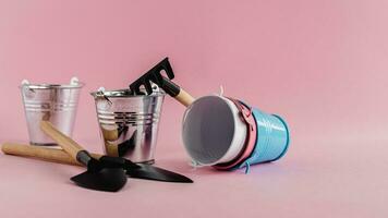 Gardening tools with tin pails or buckets on pink background photo