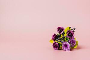 Artificial purple rose bouquet on pink background photo