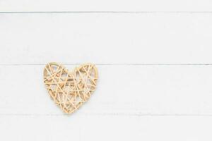 Wooden wicker heart on white table background with copy space for love and Valentine's day concept photo