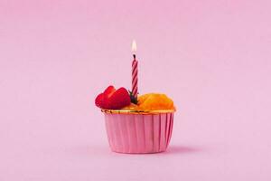 Mini paper cup of fruit or orange sponge cake with burning candle photo